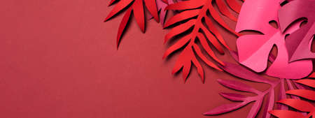 Monochromatic composition of amazing red tropical leaves made of craft paper on red backdrop. Summertime mood. Flat lay with cut out paper palm, monstera leaves. Exotic floral frame with copy space.の写真素材