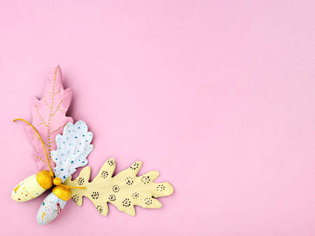 Creative autumn background. Top view of hand-painted various colors acorns and oak leaves on pink...