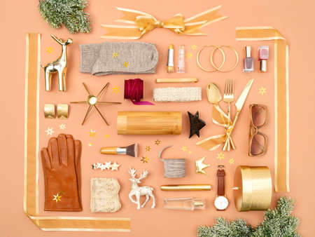 Christmas objects and gifts laid out in the shape of a gift box decorated with golden ribbon and...