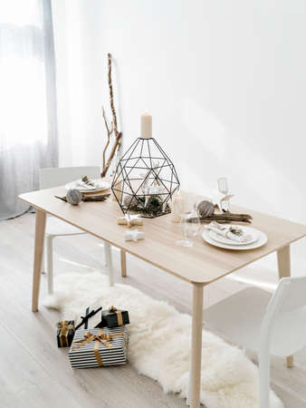 Sunlit room with table decorated for Christmas  dinner with candles, baubles and gift boxes on the floor. Minimalist eco friendly Christmas. Hygge home, simple living concept.の写真素材