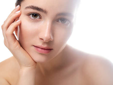 Close up portrait of a relaxed and focused pretty young woman with no makeup and glowing fresh skin on white background. Natural feminine beauty. Neutral makeup and beauty concept.の写真素材