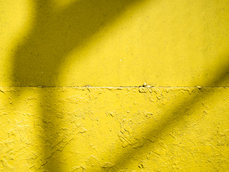 Rough textured metal background toned in main colour of the year 2021. Outdoor hand painted yellow wall with light and shadows effect. Illuminating and ultimate gray background.の写真素材