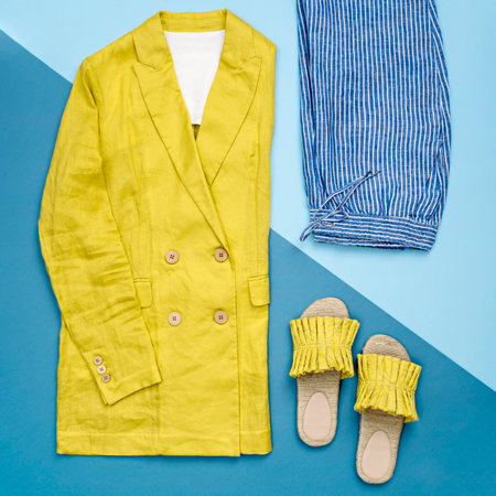 Linen female jacket and stylish slippers in trendy illuminating yellow colour on contrast blue background. Minimalist female outfit. Color of the year 2021. Main color trend. Summer sale concept.の写真素材