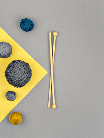 From above shot of composition of wooden needles and skeins of natural yarn on ultimate grey and illuminating yellow background. Craft, DIY and handmade. Color of the year 2021 background.の写真素材
