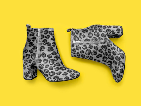 Catchy female high heels boots with animal print of ultimate grade shades on warming illuminating yellow toned backdrop. Colour of the year 2021 background. Main colour trend concept.の写真素材