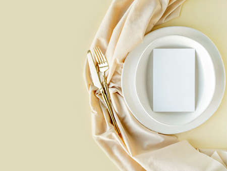 Festive wedding or birthday table setting with golden cutlery, porcelain plate and decorative textile. Blank mockup. Restaurant menu template. Flat lay, top view.の写真素材