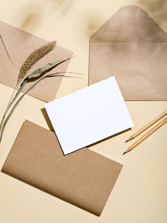 White empty card with envelopes, notebook, pencils. Blank card styled mockup with hard light and shadow. To do list, greeting card or writing a letter concept. Earth tones neutral aesthetic.の写真素材