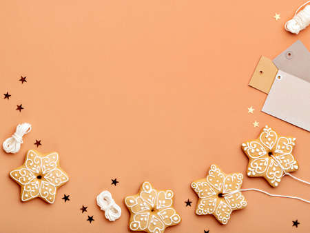 Simple Christmas or New Year background with gingerbread cookies shaped as a snowflakes, star confetti and blank gift tags. Copy space for text. Christmas, New Year and winter holidays concept.の写真素材