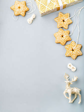 Christmas and New Year frame with space for text. Star shaped gingerbread, reindeer and gift box on light blue background, minimalist winter holiday background. Postcard or invitation mock up.の写真素材