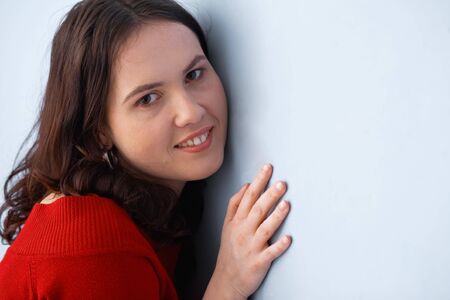 Closeup of a young beautiful woman posing and leaning on the wallの写真素材