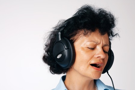 Close-up portrait of a singing elder woman with headphones.の写真素材