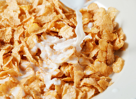 Corn flakes breakfast with milk being poured over itの写真素材