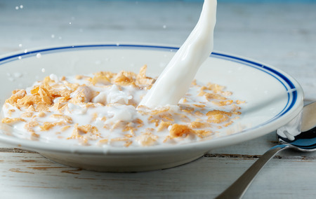 Corn flakes breakfast with milk being poured over it