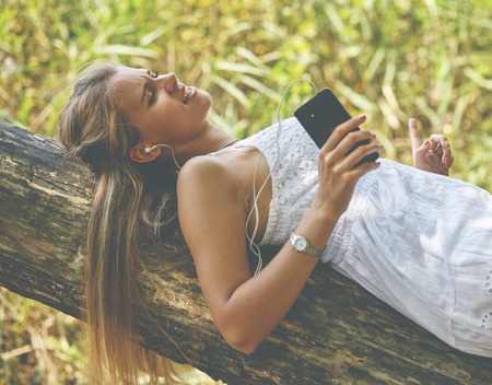 young woman with headphones listening music lying on wooden surface. Summer girl portraitの写真素材