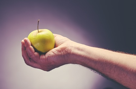 Food and dieting concept. Male hand holds green apple.