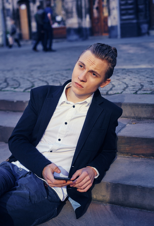 businessman sitting on a staircase, communicating through a telephoneの写真素材