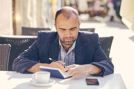 young attractive man sitting in cafe and reading book.の写真素材