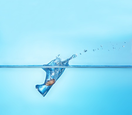 Coin splashing into water as a symbol of unstable currency.