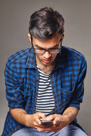 portrait of modern young man with mobile phone in a studioの写真素材