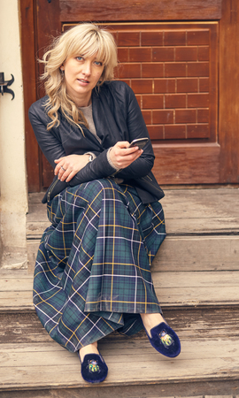 Young  woman sitting on a staircase with a smartphoneの写真素材