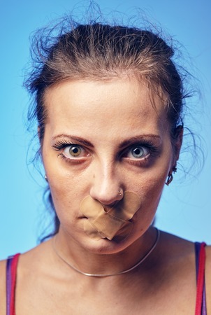 Young woman with his mouth glued with tape.の写真素材