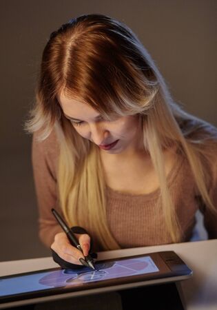 girl artist draws a digital pen on a professional tablet in her studioの写真素材