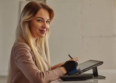girl artist draws a digital pen on a professional tablet in her studio