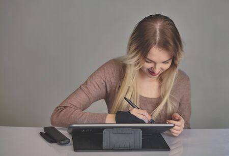 girl artist draws a digital pen on a professional tablet in her studioの写真素材