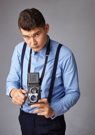 guy with the old camera at the studio. Guy shoots on an old vintage film camera with two lenses.