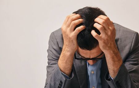 a young man holding his head. he is very concernedの写真素材