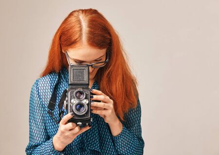 red-haired woman taking pictures using a classic cameraの写真素材