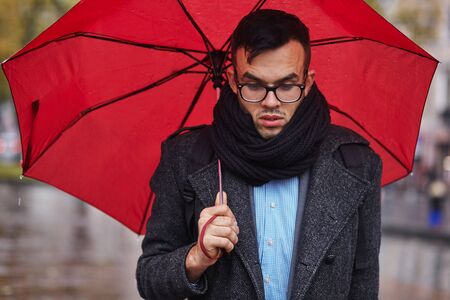 depressed businessman in the rain with umbrellaの写真素材