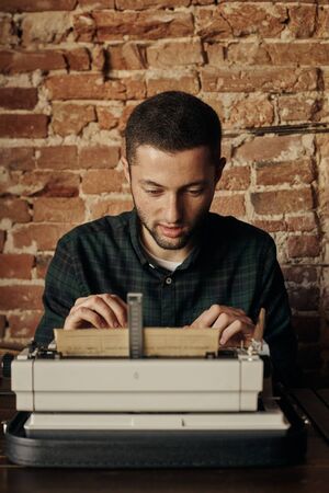 Young man writing on old typewriter.