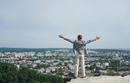 portrait of young happy businessman on top of rock. his arms are open, he loves the world