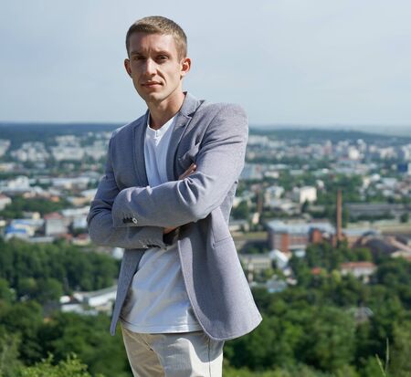 portrait of young handsome serious businessman on city background