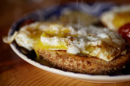 A delicious delicious and nutritious breakfast of scrambled eggs with baked tomatoes, and a baked loaf of breadの写真素材