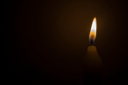 White lighted candle in the dark. Memory of the dead. Background for church theme, prayers with copy spaceの写真素材