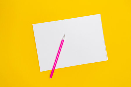 Notepad with place for copy space with pink pen on yellow background.の写真素材