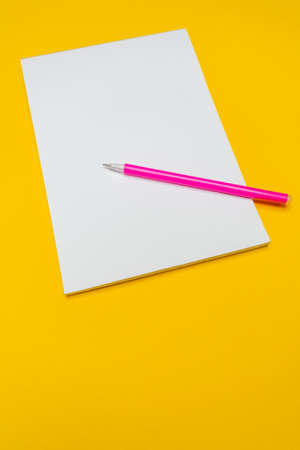 Notepad with copy space with pink pen on yellow background.Simple bright background with place for textの写真素材