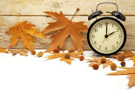 Autumn Time Change  Fall Back  Maple Leaves and an Alarm Clock on a Wooden Background