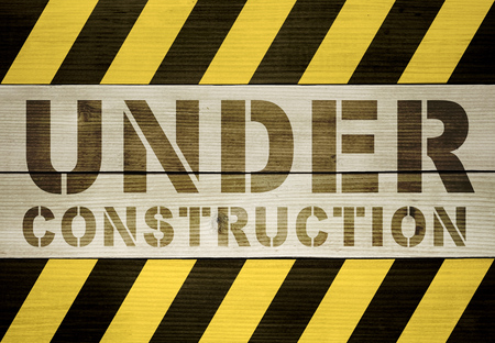 Under Construction - Printed Text on Wooden Planks Between Black and Yellow Hazard Stripesの写真素材