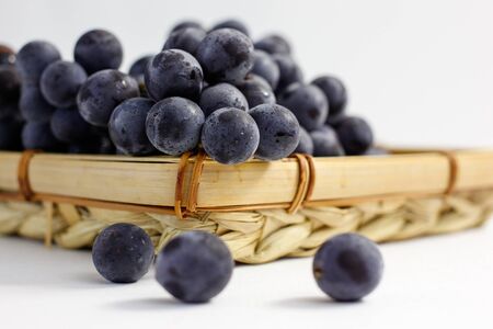 blue grapes in a basket on a white backgroundの写真素材