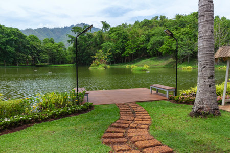 Walkway in the park with lake and mountain background, Thailand.の写真素材