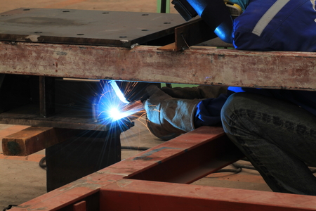 welder is welding steel structure with all safety equipment