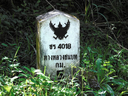 A kilometer marker in Thailand bears a black Garuda, the national emblem of Thailand. This milestone sits next to rural road 4018 at kilometer 5.のeditorial素材