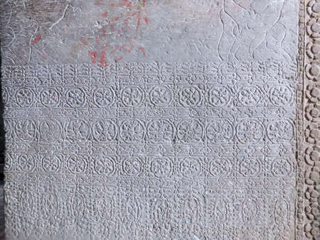 The lower part of a huge rectangular stone column at Angkor Wat in Cambodia is adorned with several...