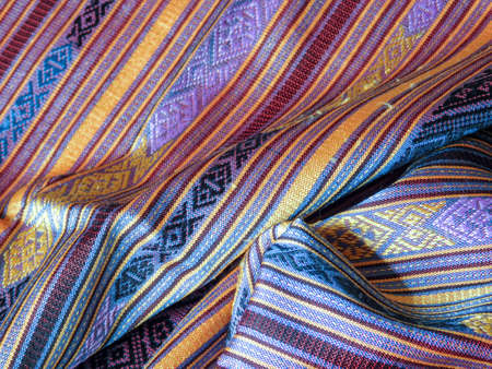 The elegant patterns of a Laotian silk scarf. Part of a handwoven silk fabric in a range of beautiful subdued shades of blue and gold.の写真素材