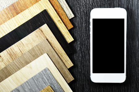 Mobile screen order Samples of laminate and vinyl floor tile on wooden Background for new...