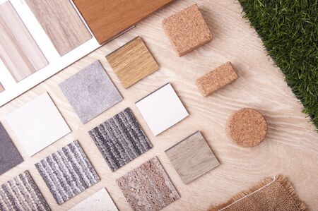 Materials Concept. Top view of sample materials on wood background. Wood laminate, vinyl flooring laminate tiles, plywood, wood laminate veneer, sackcloth, artificial grass on wooden floor.の写真素材