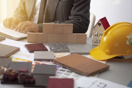 Man in Suit typing Wood materials at work desk for new construction project. Materials construction.の写真素材